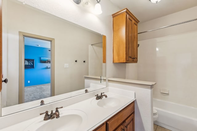 full bath featuring toilet, double vanity, shower / washtub combination, and a sink