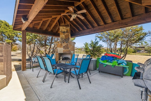 view of patio with a gazebo, an outdoor stone fireplace, area for grilling, and fence