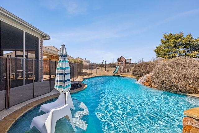 view of swimming pool featuring a sunroom, a playground, fence, and a fenced in pool