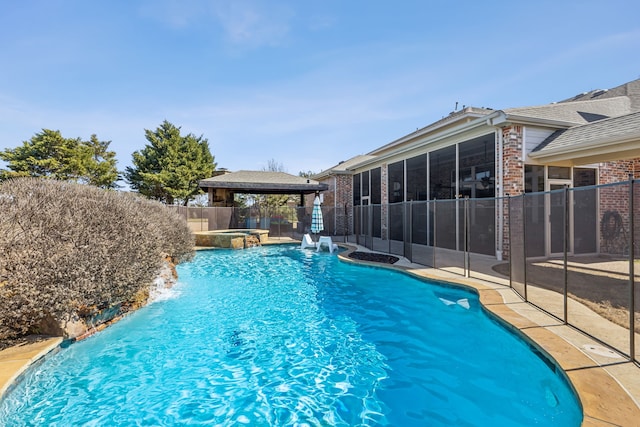 view of swimming pool with a pool with connected hot tub, a sunroom, fence, and a gazebo