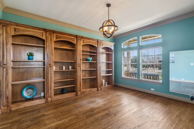 spare room with baseboards, a notable chandelier, ornamental molding, and wood finished floors