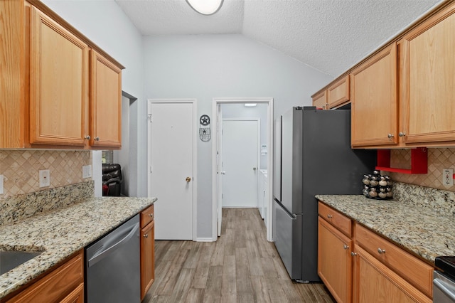 kitchen with lofted ceiling, light stone counters, stainless steel appliances, a textured ceiling, and light wood-style floors