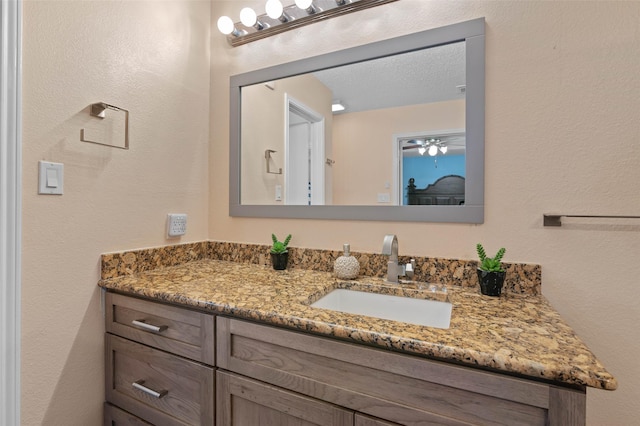 bathroom with a textured wall and vanity