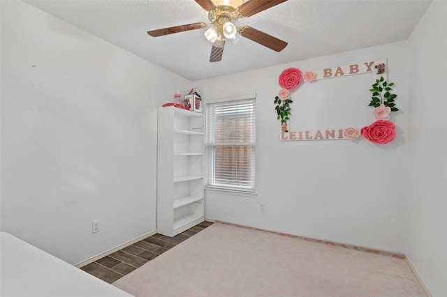 spare room featuring a ceiling fan, a textured ceiling, baseboards, and wood finished floors