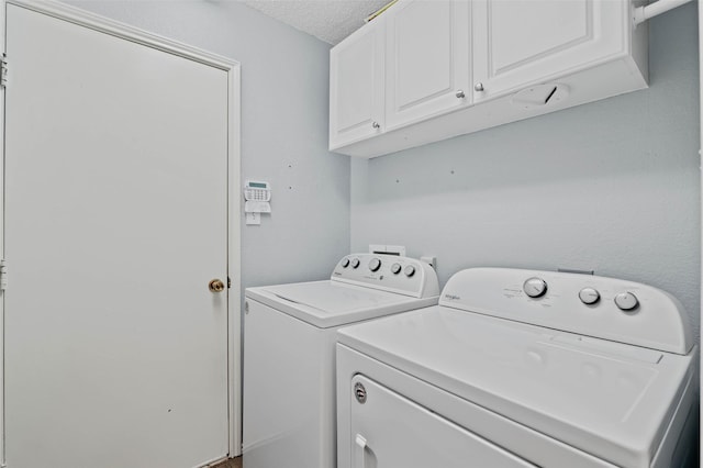 laundry room with cabinet space, washer and clothes dryer, and a textured ceiling