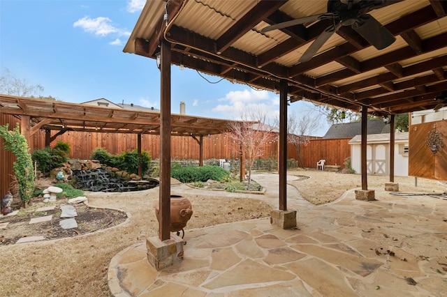 view of patio / terrace featuring an outbuilding, a storage shed, a fenced backyard, and a ceiling fan