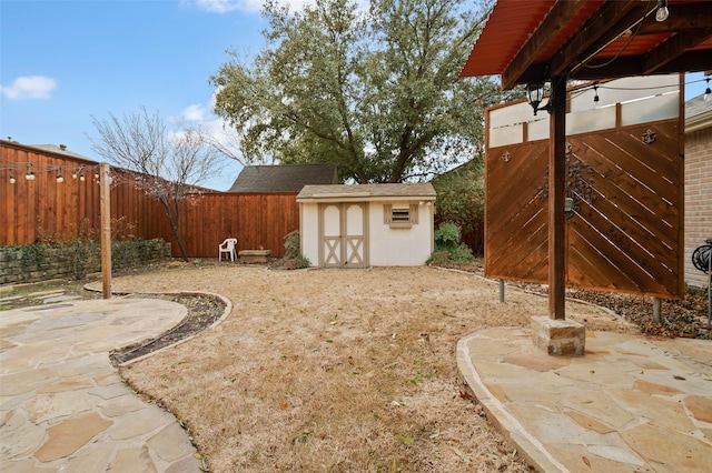 view of yard featuring an outbuilding, a storage unit, a patio area, and a fenced backyard