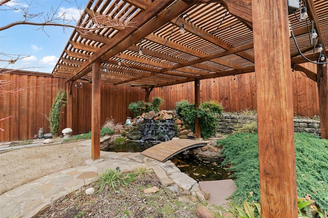 view of yard with a fenced backyard, a small pond, and a pergola