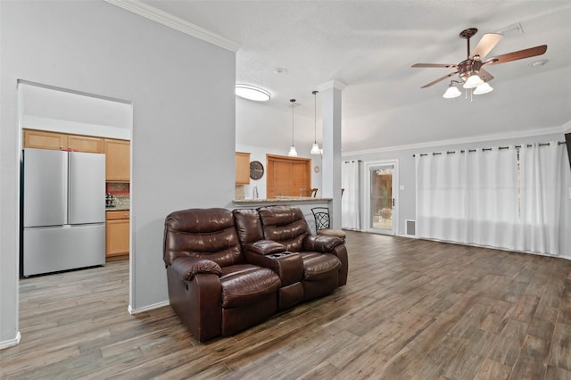 living area featuring a ceiling fan, vaulted ceiling, a textured ceiling, crown molding, and light wood-style floors