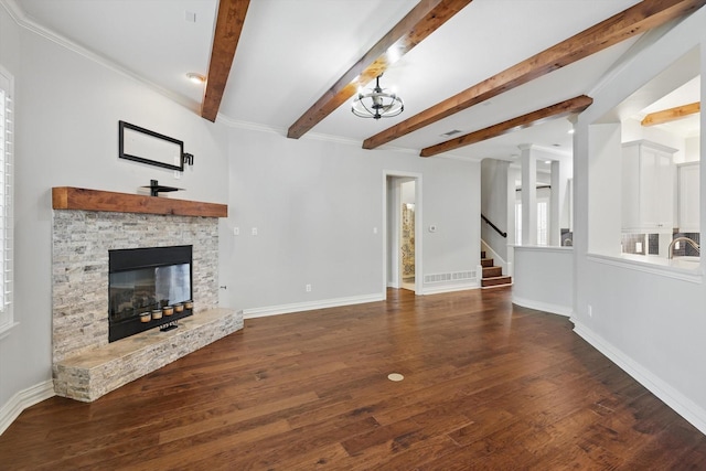 unfurnished living room featuring a stone fireplace, wood finished floors, baseboards, stairway, and beam ceiling