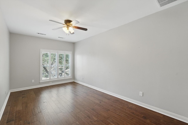 spare room with a ceiling fan, visible vents, dark wood finished floors, and baseboards