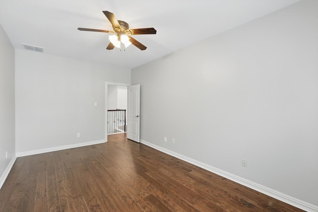 unfurnished room featuring dark wood-style floors, a ceiling fan, visible vents, and baseboards