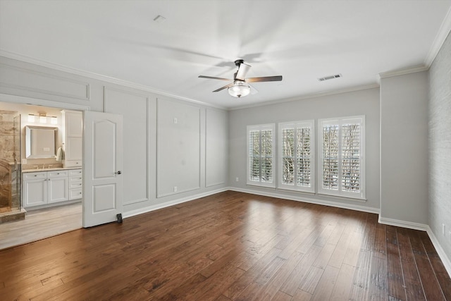 unfurnished bedroom with visible vents, a decorative wall, wood finished floors, and ornamental molding