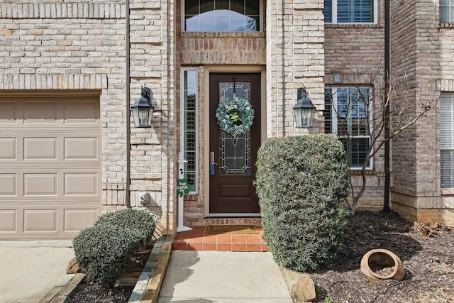 view of exterior entry featuring brick siding and an attached garage