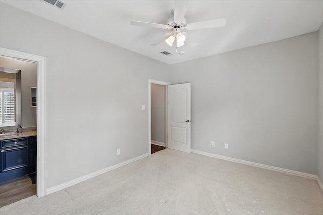 unfurnished bedroom with light colored carpet, visible vents, ensuite bath, and baseboards