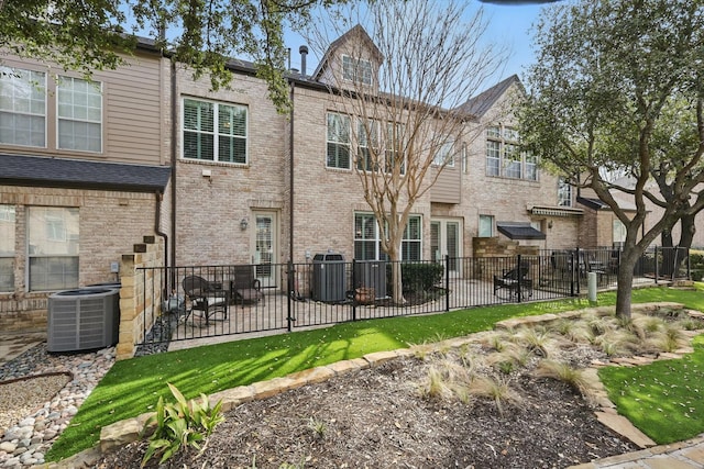 back of property featuring central air condition unit, fence, and brick siding