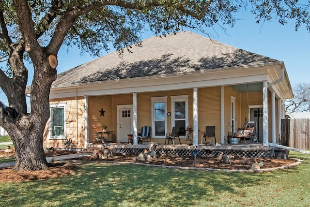 view of front facade featuring a lawn, roof with shingles, and fence