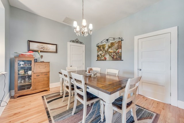 dining space featuring visible vents, baseboards, an inviting chandelier, and light wood-style flooring