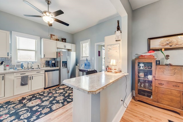 kitchen featuring a peninsula, plenty of natural light, a sink, light countertops, and appliances with stainless steel finishes