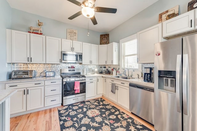 kitchen with backsplash, appliances with stainless steel finishes, light countertops, and a sink