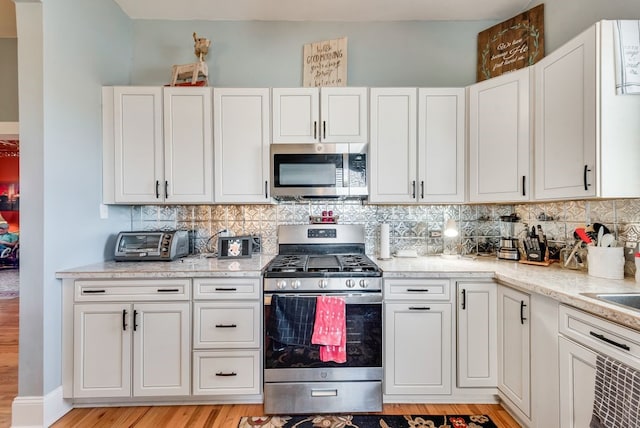 kitchen with stainless steel appliances, backsplash, and white cabinets