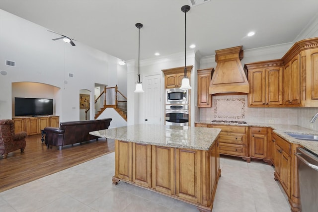 kitchen featuring visible vents, custom range hood, a sink, light stone counters, and appliances with stainless steel finishes