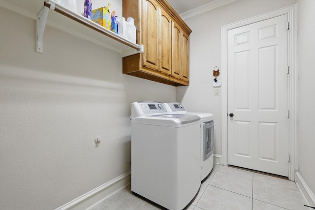 clothes washing area featuring light tile patterned floors, baseboards, cabinet space, ornamental molding, and washer and clothes dryer