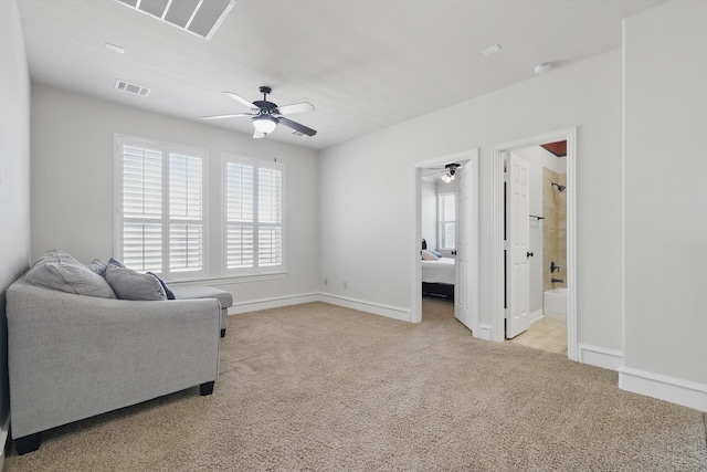 sitting room with a wealth of natural light, visible vents, light colored carpet, and ceiling fan