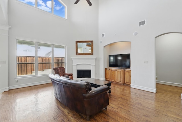 living area with a fireplace, wood finished floors, visible vents, and ceiling fan