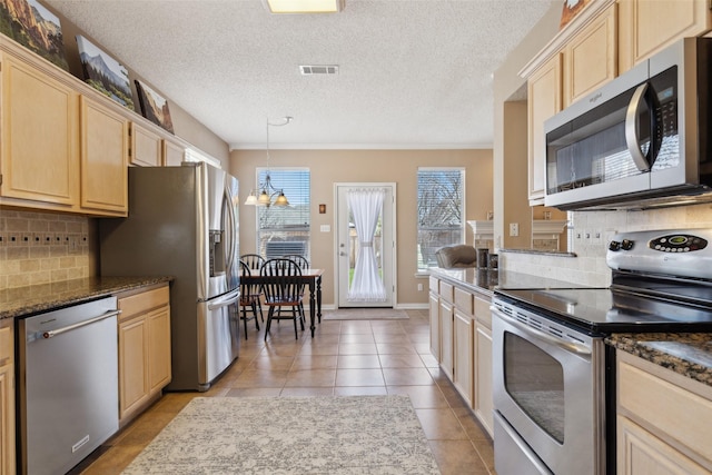 kitchen with light tile patterned floors, tasteful backsplash, an inviting chandelier, appliances with stainless steel finishes, and light brown cabinetry