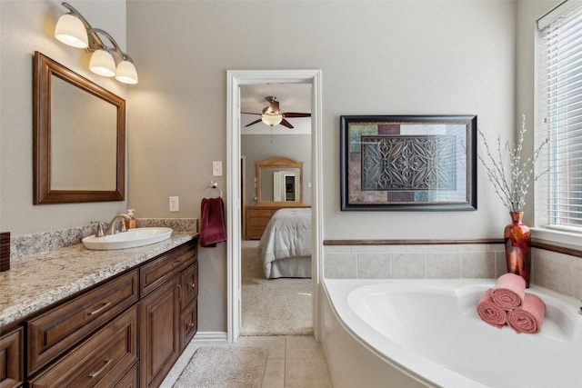 ensuite bathroom featuring ceiling fan, connected bathroom, vanity, a bath, and tile patterned floors