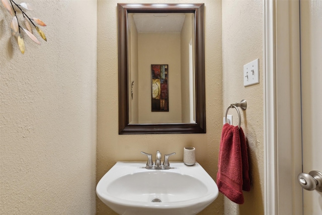 bathroom with a textured wall and a sink