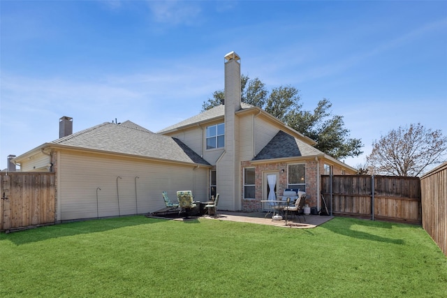 rear view of house with a fenced backyard, a chimney, a lawn, and brick siding