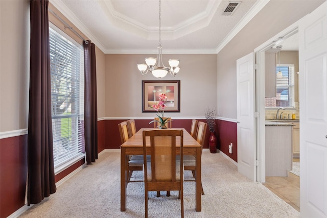 dining area featuring a tray ceiling, light colored carpet, a notable chandelier, and visible vents