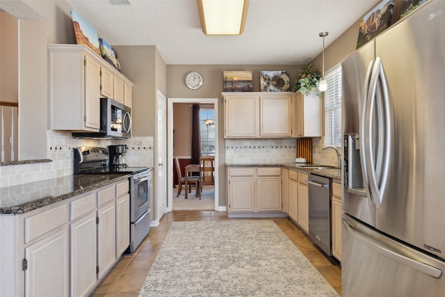 kitchen featuring a healthy amount of sunlight, a sink, stainless steel appliances, and dark stone countertops