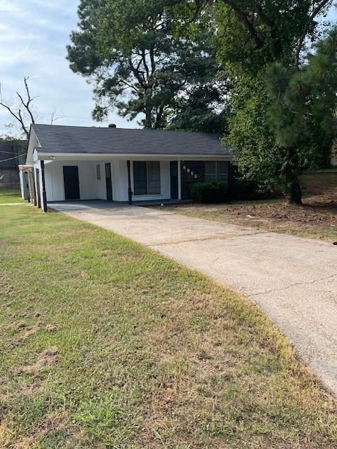 ranch-style home featuring a carport, a front yard, and concrete driveway