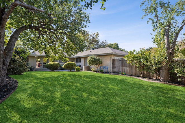 view of front of home with central AC, a front lawn, fence, and brick siding