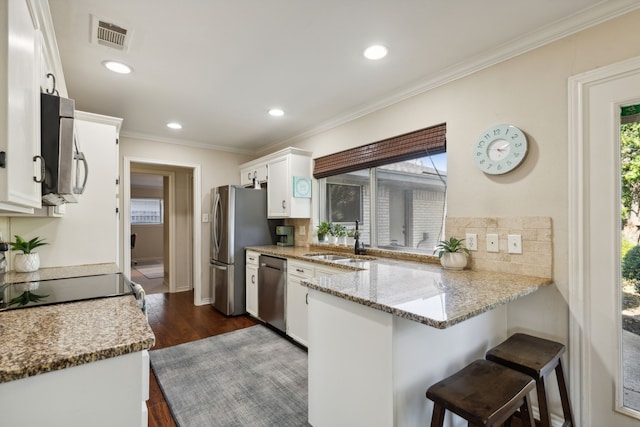 kitchen with white cabinets, visible vents, a sink, a peninsula, and appliances with stainless steel finishes