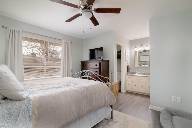 bedroom with light wood finished floors, baseboards, connected bathroom, ceiling fan, and a sink