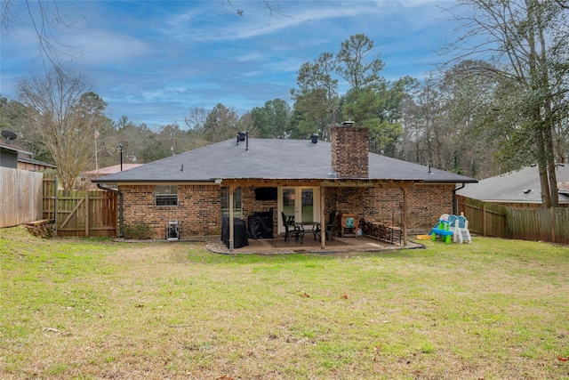 rear view of property featuring a yard, brick siding, a patio, and a fenced backyard