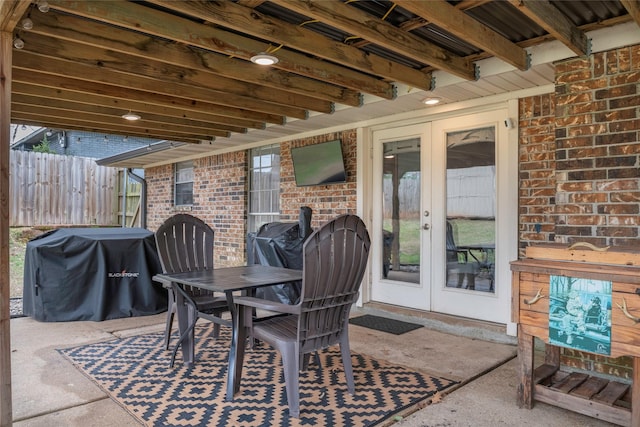 view of patio featuring french doors, outdoor dining space, fence, and a grill