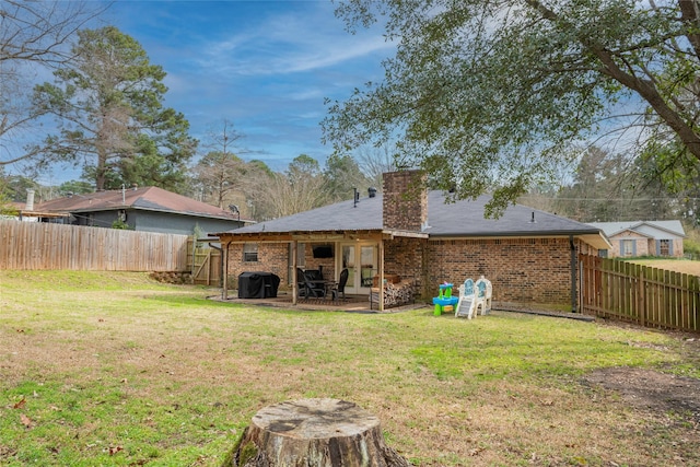 rear view of property featuring brick siding, a lawn, and a patio area