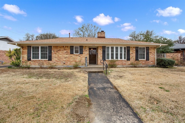 ranch-style house featuring a chimney, a front lawn, and brick siding