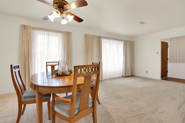 dining space with light colored carpet, a healthy amount of sunlight, ceiling fan, and visible vents