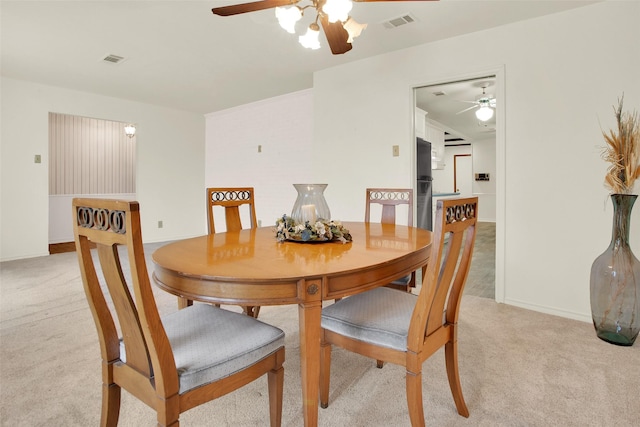 dining room featuring light carpet, a ceiling fan, visible vents, and baseboards