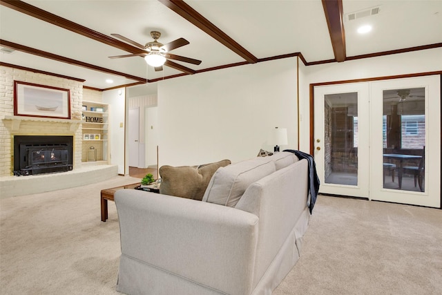 living area featuring a brick fireplace, beam ceiling, light carpet, and visible vents