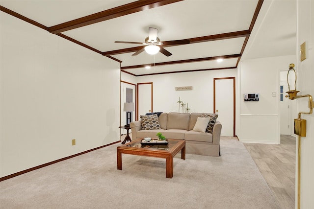 living area featuring baseboards, a ceiling fan, light colored carpet, ornamental molding, and beamed ceiling