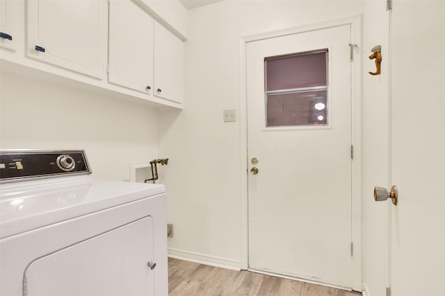 clothes washing area featuring baseboards, cabinet space, washer / dryer, and light wood-style floors