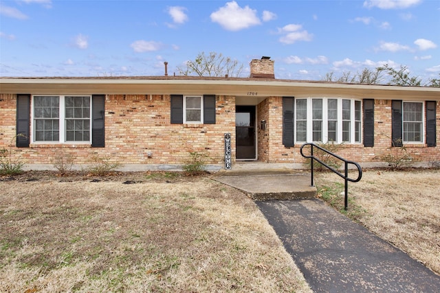 single story home featuring brick siding and a chimney