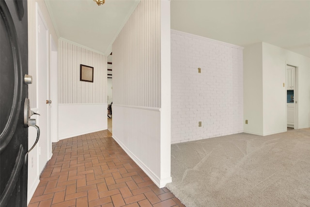 interior space featuring brick floor, carpet flooring, ornamental molding, and brick wall